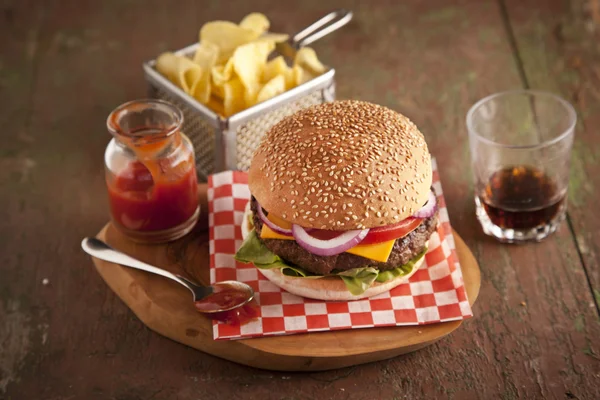 Classic deluxe cheeseburger with lettuce, onions, tomato and pickles on a sesame seed bun — Stock Photo, Image