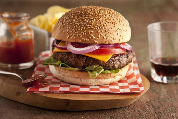 Klassischer Deluxe-Cheeseburger mit Salat, Zwiebeln, Tomaten und Essiggurken auf einem Sesamkernbrötchen — Stockfoto