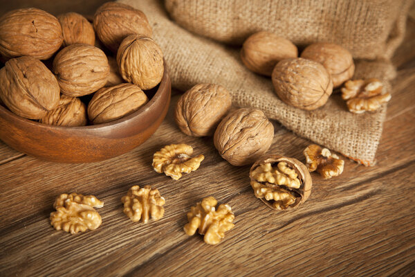 Walnut kernels and whole walnuts on rustic old wooden table