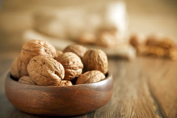 Noyaux de noix et noix entières sur une vieille table rustique en bois — Photo