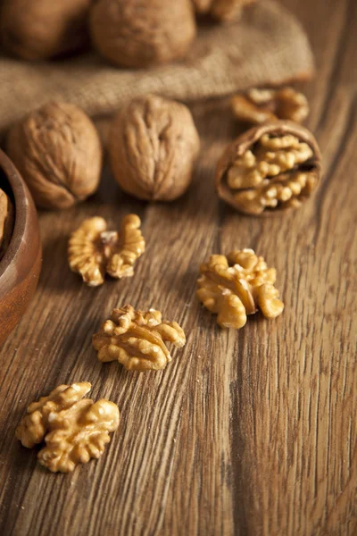 Noyaux de noix et noix entières sur une vieille table rustique en bois — Photo