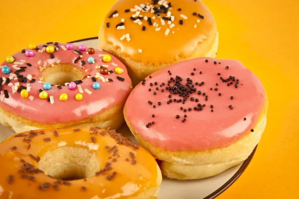 Donuts frescos coloridos no fundo amarelo — Fotografia de Stock