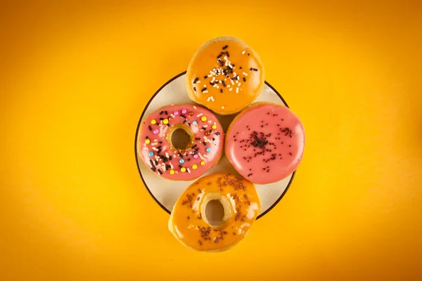 Colorful fresh doughnuts on yellow background — Stock Photo, Image