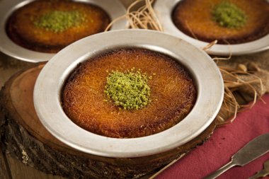 Delicious traditional Turkish kunefe with pistachio on it. Served hot and with syrup clipart