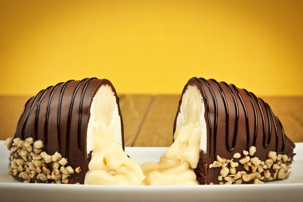 Chocolate coated bananas cake with nuts yellow background — Stock Photo, Image