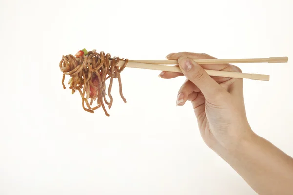 Mão segurando macarrão vegetal com pauzinhos, isolado em branco — Fotografia de Stock