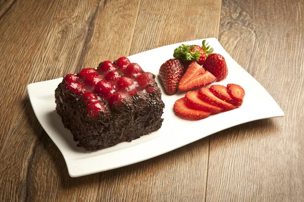 Piece of chocolate cake with icing and fresh berry — Stock Photo, Image