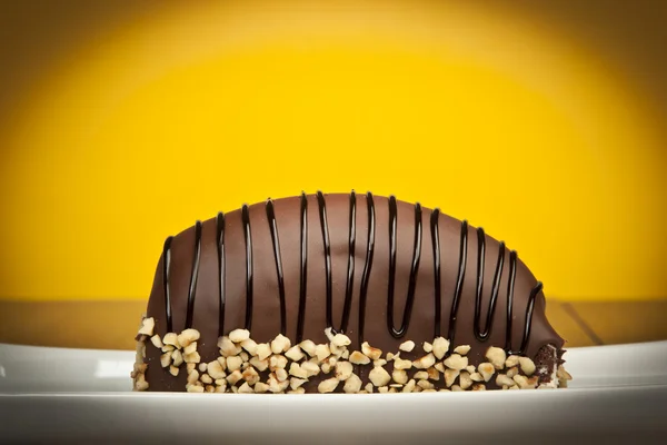 Pastel de plátanos recubierto de chocolate con nueces fondo amarillo —  Fotos de Stock