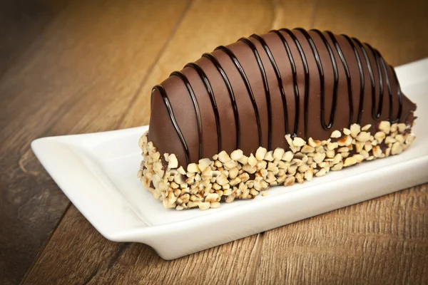 Pastel de plátanos recubierto de chocolate con nueces en mesa de madera — Foto de Stock