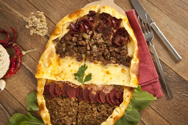 Zelfgemaakte, traditionele Turkse maaltijd pizza pide gevuld met vlees, kaas, pastirma en worst — Stockfoto