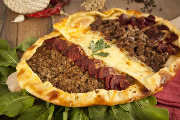 Homemade traditional Turkish meal pizza pide stuffed with meat, cheese, pastirma and sausage — Stock Photo, Image