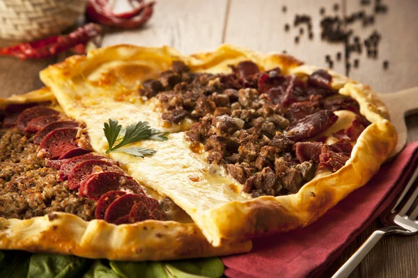 Homemade traditional Turkish meal pizza pide stuffed with meat, cheese, pastirma and sausage — Stock Photo, Image