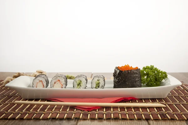 Макидзуси. Вкусные суши-роллы из кани, тобико и маки на белой тарелке — стоковое фото