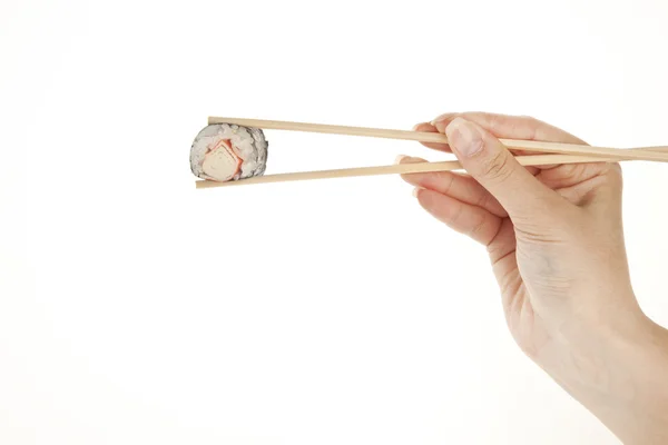 Mão segurando rolo de sushi com pauzinhos, isolado em branco — Fotografia de Stock