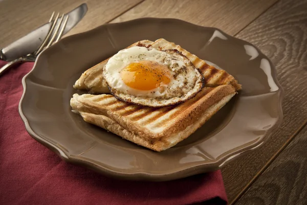 Яичница с тостами на деревянном столе из коричневой тарелки — стоковое фото