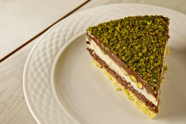 Pastel de queso pistacho, tarta de mousse con decoración de nueces en un plato blanco — Foto de Stock