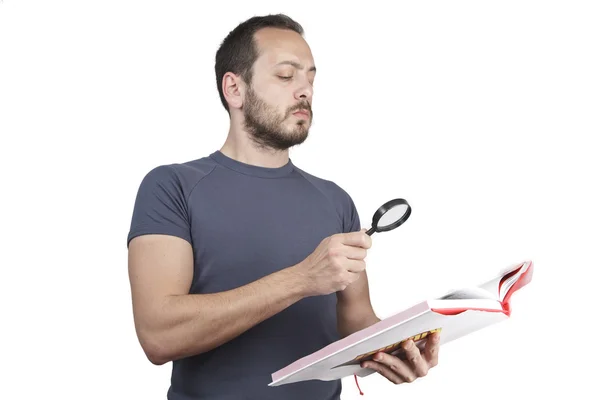 Verbaasd man die door een vergrootglas met boek — Stockfoto