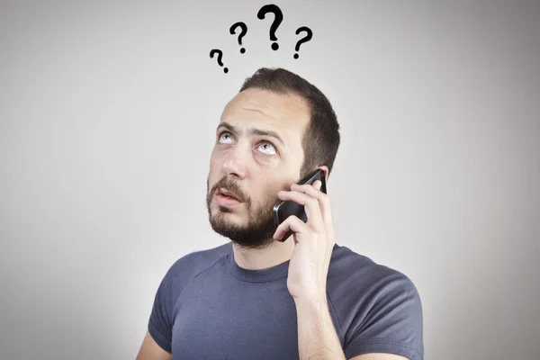 Young man gesturing while answering smart phone not understood — Stock Photo, Image