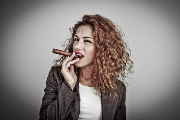 Closeup portrait of a young businesswoman smoking cigar and blowing smoke, on dark background — Stock Photo, Image