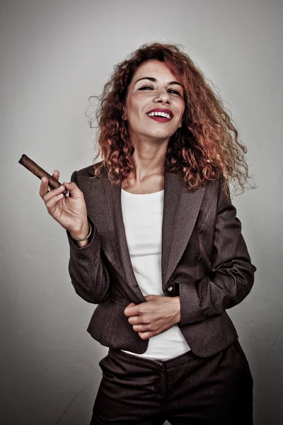 Closeup portrait of a young businesswoman smoking cigar and blowing smoke, on dark background — Stock Photo, Image