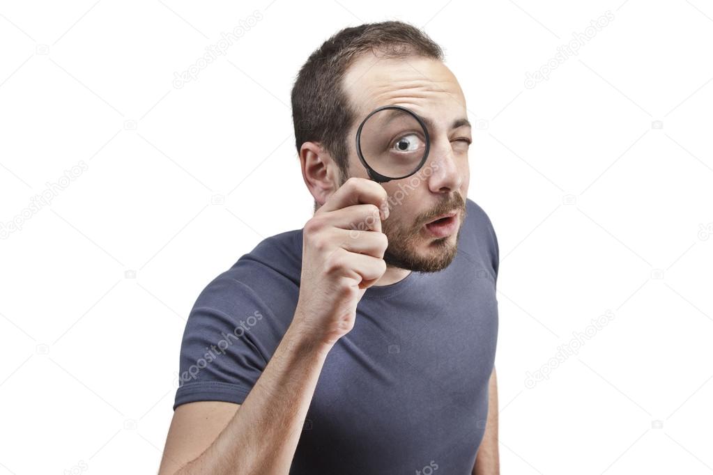 Astonished man looking through a magnifying glass