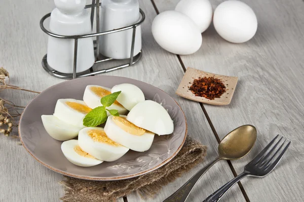 Jajka na twardo z liści mięty i biały drewniany stół — Zdjęcie stockowe