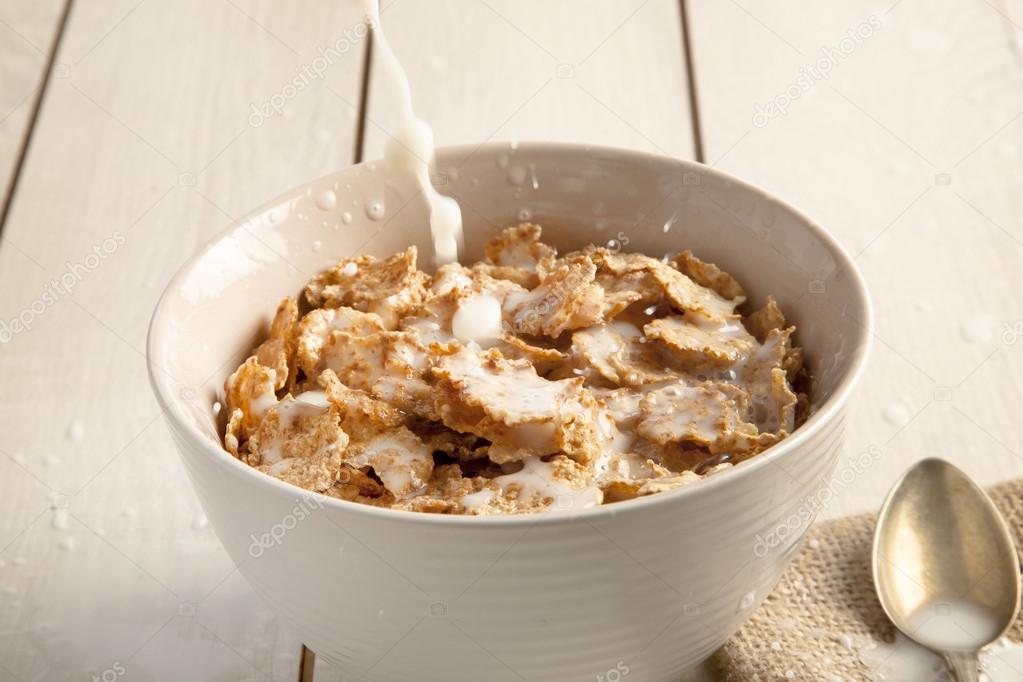 Bowl of sugar-coated corn flakes and spoon wooden background