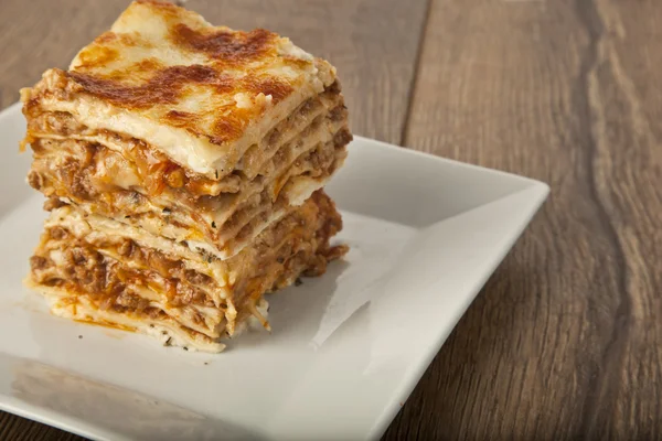 Een stuk van Italiaanse lasagne Bolonese op een vierkante plaat — Stockfoto