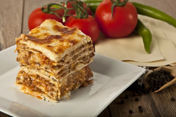 Een stuk van Italiaanse lasagne Bolonese op een vierkante plaat — Stockfoto