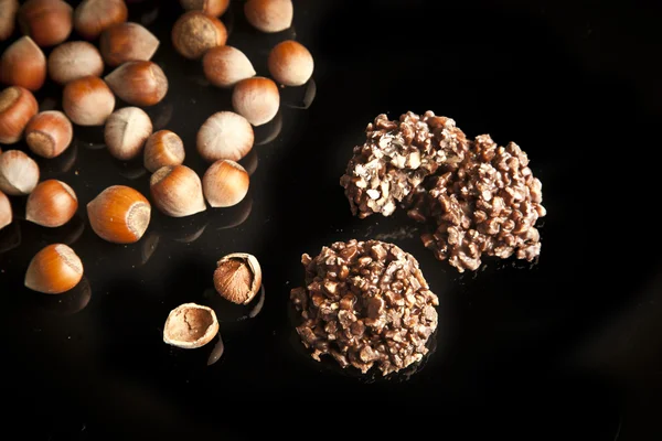 Κομμάτια σοκολάτας με ξηρούς καρπούς σε μαύρο φόντο — Φωτογραφία Αρχείου