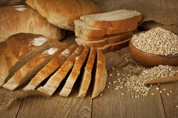 Pain de blé, graines de blé et tranches de pain avec fond en bois — Photo