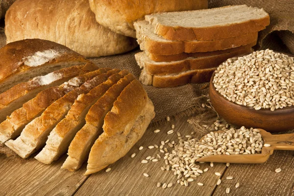 Weizenbrot, Weizensamen und Brotscheiben mit Holzhintergrund — Stockfoto