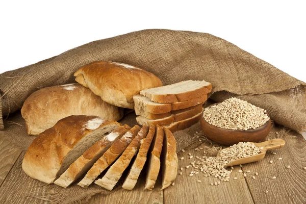 Pane di grano, semi di grano e fette di pane con sfondo in legno — Foto Stock
