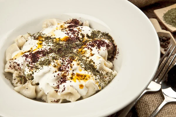 Turkish Manti manlama on plate with red pepper, tomatoes sauce, — Stock Photo, Image