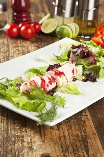 Lobster surimi slices on a platter with green and purple vegetables and limes — Stock Photo, Image