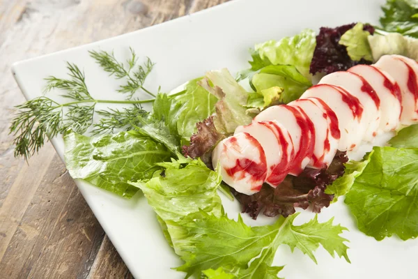 Fatias de surimi de lagosta em uma bandeja com vegetais e limas verdes e roxas — Fotografia de Stock