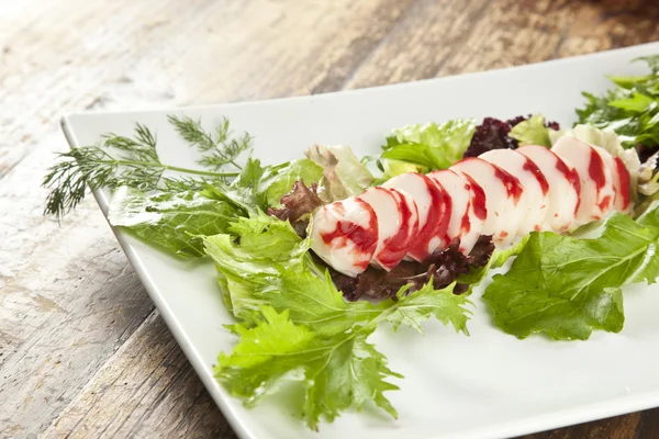 Fatias de surimi de lagosta em uma bandeja com vegetais e limas verdes e roxas — Fotografia de Stock