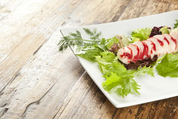 Fatias de surimi de lagosta em uma bandeja com vegetais e limas verdes e roxas — Fotografia de Stock