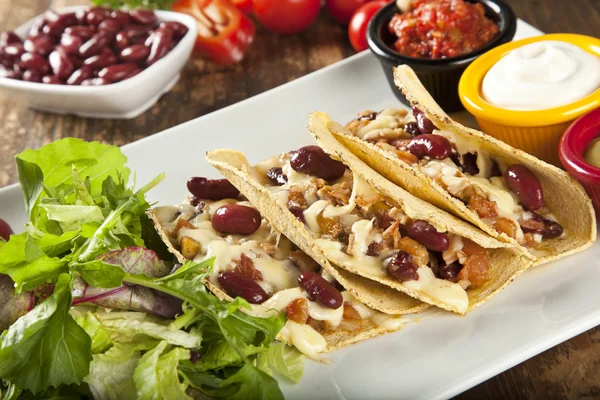 A plate of delicious tacos with lime, tomato, lettuce, and cheese. — Stock Photo, Image