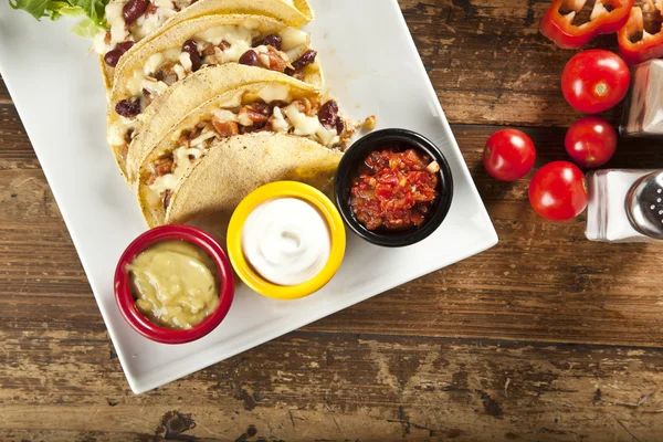 Um prato de deliciosos tacos com limão, tomate, alface e queijo . — Fotografia de Stock