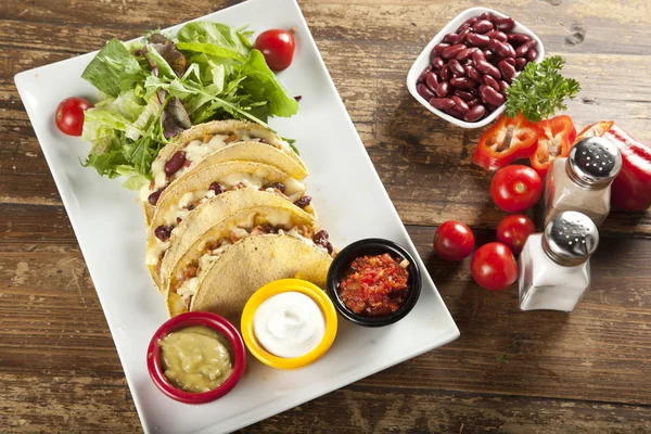 Un plato de deliciosos tacos con lima, tomate, lechuga y queso . — Foto de Stock