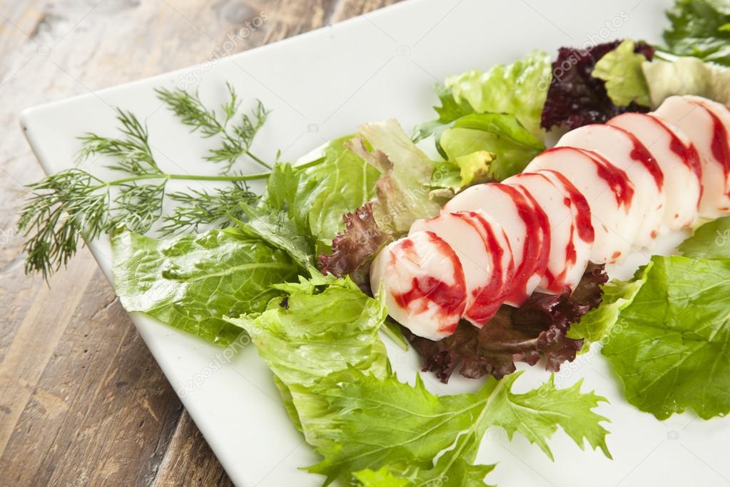 Lobster surimi slices on a platter with green and purple vegetables and