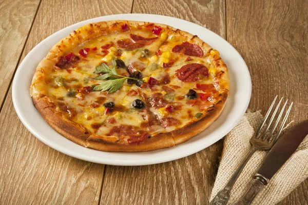 Pizza italiana entera sobre mesa de madera con ingredientes — Foto de Stock