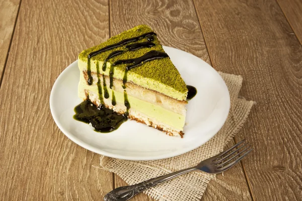 Pistachio cheesecake, mousse cake with nuts decoration on a wooden table — Stock Photo, Image