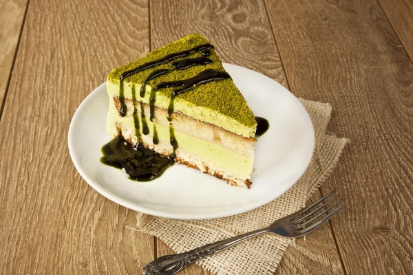 Pistazienkäsekuchen, Moussekuchen mit Nussdekoration auf einem Holztisch — Stockfoto