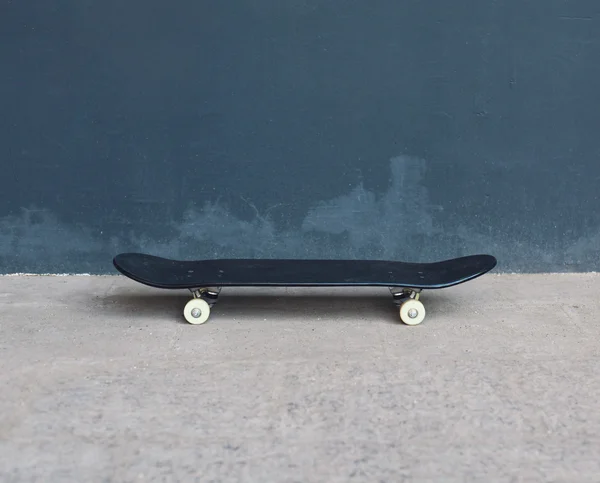 Skateboard op de straat over gestructureerde stedelijke achtergrond zwart — Stockfoto