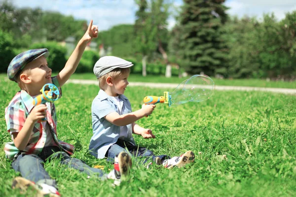 Glada två pojkar barn sitter på gräs leker och har kul — Stockfoto