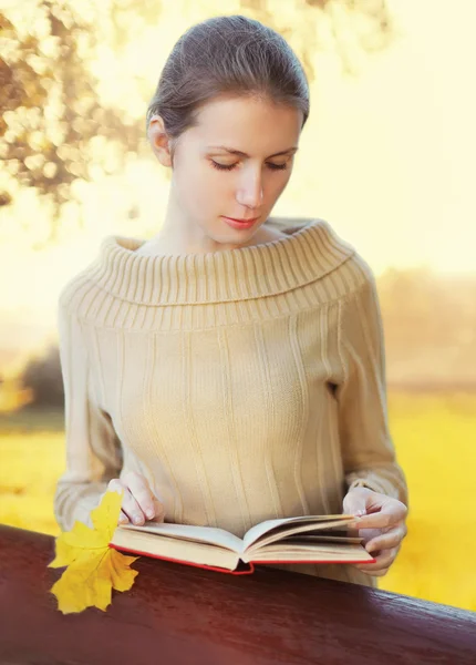 Portrait young woman reading book in sunny autumn park — Stock Photo, Image