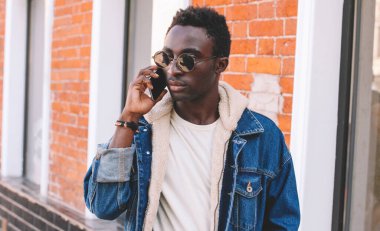 Bir şehir caddesinde yürürken akıllı telefondan konuşan Afrikalı bir adamın portresi.