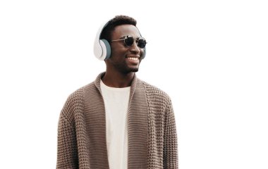 Beyaz arka planda izole edilmiş müzik dinleyen, kablosuz kulaklıklı mutlu Afrikalı adamın portresi.